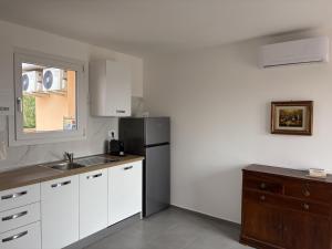 a kitchen with white cabinets and a black refrigerator at Attico Terracotta in Borgo Bainsizza