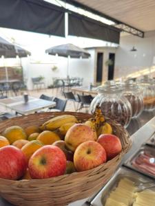 a basket of apples and bananas on a table at Hotel Mão de Fatima in Aparecida