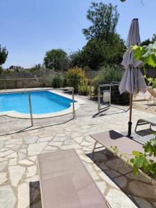 a swimming pool with an umbrella and a chair and a table at Casa Tere in Codo