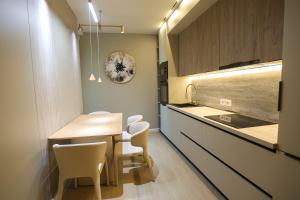 a kitchen with a wooden table and white chairs at Blue Coast - Villa 1 Perla Resort in Lalëz