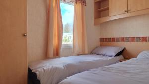 two beds in a room with a window at Sanderling Bluebird 14 in Cruden Bay
