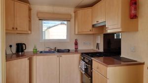 a kitchen with wooden cabinets and a stove top oven at Sanderling Bluebird 14 in Cruden Bay