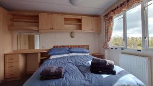 a bedroom with a bed with blue sheets and windows at Sanderling Bluebird 14 in Cruden Bay