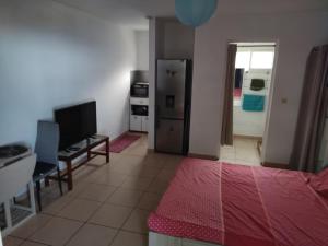 a room with a bed and a table and a kitchen at Studio Les Avirons centre ville in Les Avirons