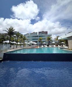 a large swimming pool with palm trees and a building at Cobertura 435 - In mare bali in Parnamirim +5 photos