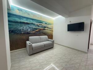 a living room with a chair and a painting of the ocean at SeaMood Casa Vacanze in Praia a Mare