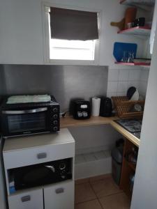 a small kitchen with a microwave on a counter at Studio Les Avirons centre ville in Les Avirons