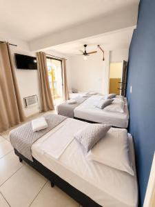 a bedroom with two beds and a blue wall at Hotel Mão de Fatima in Aparecida