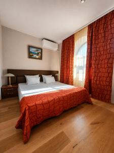 a bedroom with a bed with a red blanket and a window at Family Art Hotel Gallery in Pleven +27 photos