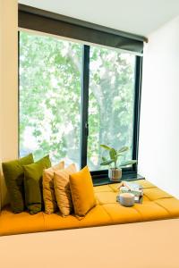 a yellow couch with pillows in front of a window at City Hotel in Abbottabad
