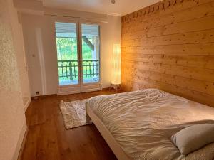a bedroom with a bed and a wooden wall at Duplex familial à la campagne in Orcier