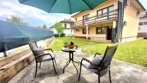 a patio with two chairs and a table with an umbrella at Ilidza Holiday Home in Sarajevo