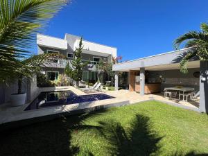 a house with a swimming pool in front of a yard at Linda casa em Paraty in Paraty