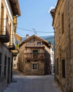 an old stone building with a balcony in an alley at Casa rural en La Adrada con jardín in La Adrada
