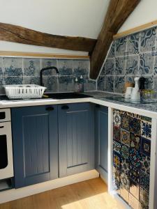 a kitchen with blue cabinets and tiles on the wall at Villa Ô Bedroom2 studio entier in Chasnay
