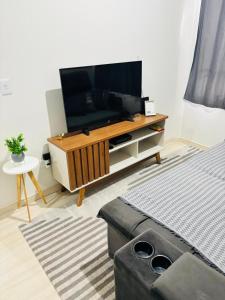 a living room with a flat screen tv on a entertainment center at Apartamento 2 quartos e 2 camas casal in Cascavel