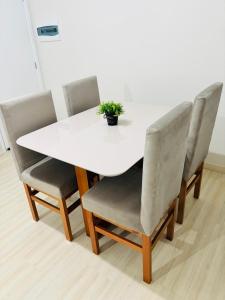 a white table and chairs with a potted plant on it at Apartamento 2 quartos e 2 camas casal in Cascavel +16 photos