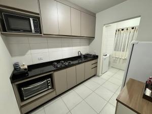 a kitchen with a stove and a microwave at Apartamento 2 quartos e 2 camas casal in Cascavel