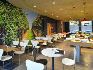 a restaurant with tables and chairs and a wall mural at ibis Caxias do Sul in Caxias do Sul