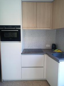 a kitchen with white cabinets and a stove top oven at Klauwaards appartement in Kortrijk