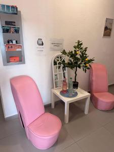 two pink chairs and a table with a potted plant at Open Tours in Ełk