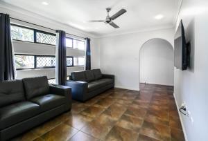 a living room with a couch and a flat screen tv at WhitsunStays - Casa Crimson in Mackay