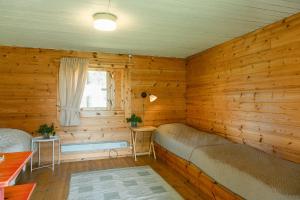 a room with wooden walls with a couch and a window at Taipaleen luomutila in Petäjävesi +35 photos