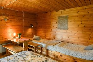 a bedroom with two beds and a wooden wall at Taipaleen luomutila in Petäjävesi