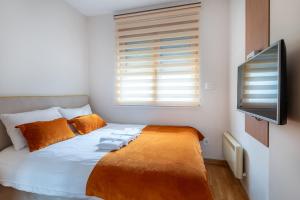 a bedroom with a bed and a flat screen tv at Egoiste Guesthouse Zlatibor Center in Zlatibor