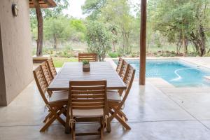 a dining room table with chairs and a swimming pool at Afrikaya Villas in Hoedspruit