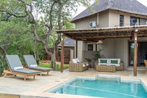 a patio with a pool and chairs and a house at Afrikaya Villas in Hoedspruit