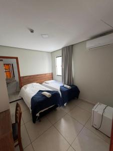 a hotel room with a bed and a window at Hotel Vitória in Vitória da Conquista