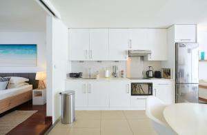 a white kitchen with white cabinets and a table at Beautiful Flat in Mont Choisy in Mont Choisy