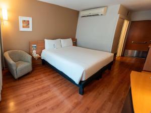 a bedroom with a large bed and a chair at Novotel Lima San Isidro in Lima