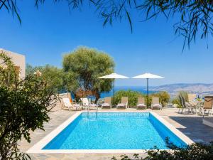 a pool with chairs and umbrellas and the ocean at Villa Panorama Tessera in Drousha