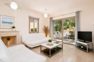 a living room with a white couch and a tv at Villa Panorama Tessera in Drousha