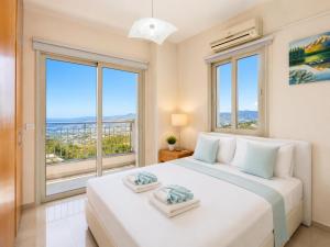 a bedroom with a large white bed with large windows at Villa Panorama Tessera in Drousha +12 photos