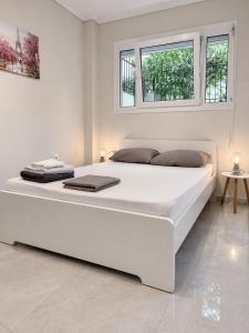 a large white bed in a white room with windows at Xsoma Flats "Studio" in Thessaloniki