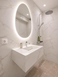 a white bathroom with a sink and a mirror at Xsoma Flats "Studio" in Thessaloniki