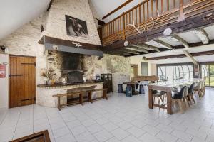 a large kitchen with tables and a stone wall at La Ferme Des Bigornes in Châtillon-sur-Indre