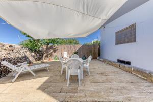 eine Terrasse mit Tisch und Stühlen und ein weißes Gebäude in der Unterkunft Da lu Pira in Patù