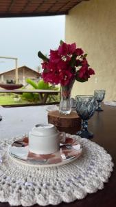 a table with a plate and a vase of flowers at Pousada Makai - Cajueiro da Praia in Barra Grande