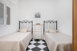 two beds in a bedroom with a checkered floor at Playa de Conil in Conil de la Frontera