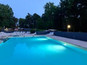 a large swimming pool with white chairs and a fence at Camping La Dune Blanche - Daly's home in Camiers
