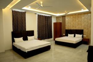 two beds in a hotel room with two beds sidx sidx sidx at Hotel Maurya Greens in Banbāsa