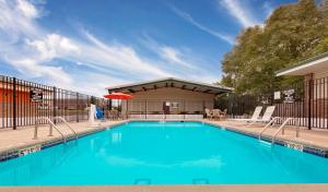 einen Pool mit Stühlen und einem Sonnenschirm in der Unterkunft Super 8 by Wyndham Siloam Springs in Siloam Springs
