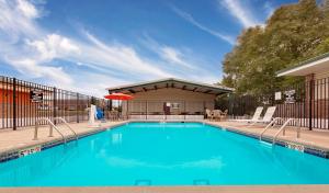 a swimming pool with chairs and an umbrella at Super 8 by Wyndham Siloam Springs in Siloam Springs