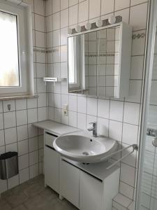 a white bathroom with a sink and a mirror at Ruhiges City-Apartment mit Balkon in Selb