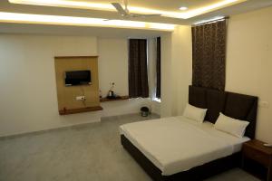 a bedroom with a bed and a television in it at Hotel Maurya Greens in Banbāsa +34 photos