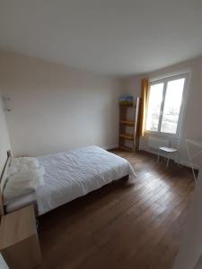 a white bedroom with a bed and a window at Les Tournesols in Égletons
